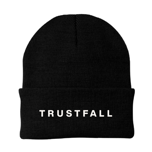 Back view of a black roll-over beanie with white TRUSTFALL text on the back